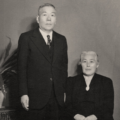 Jukichi Harada in a dark suit and tie and Ken Harada seated in a dark dress.