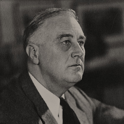 President Franklin D. Roosevelt wearing a dark suit and tie, looking into the distance.