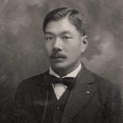 Jukichi Harada with a moustache, in a dark three piece suit and dark bow tie.