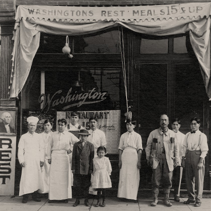 Jukichi, Masa Atsu, and Mine Harada, with restaurant staff in front of the Haradas’ Washington Restaurant. Jukichi and many of the staff are dressed in white restaurant uniforms.